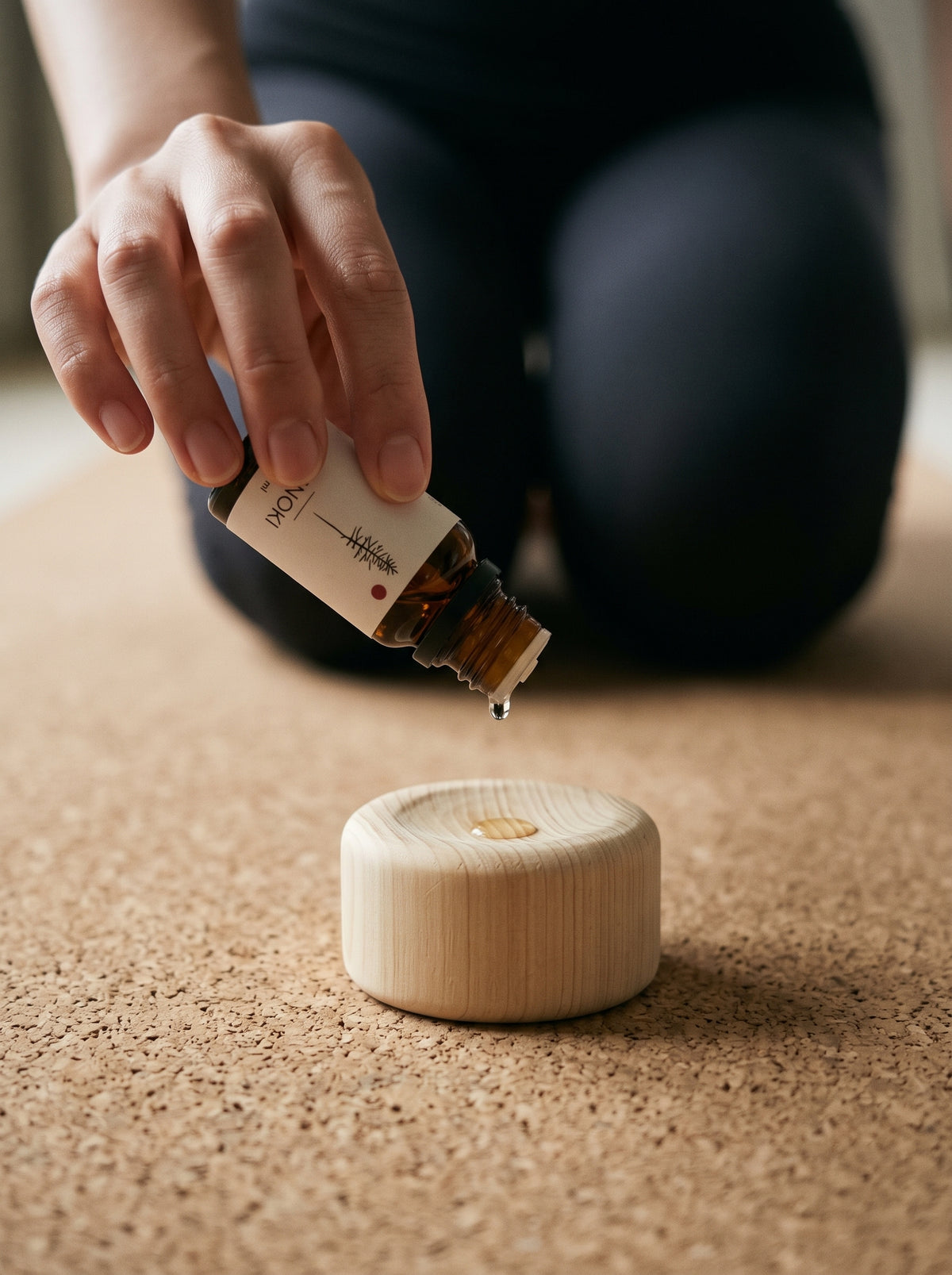 A drop of hinoki oil falling onto the Hinoki Forest Block at the top of a cork yoga mat